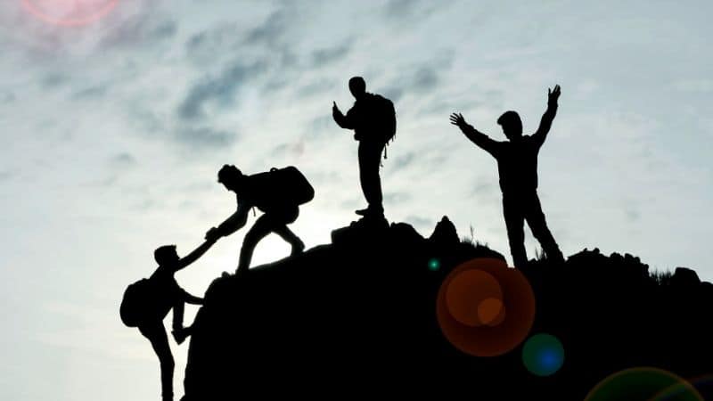 Build teams to help everyone succeed. In the picture, you have 4 people who climb an elevated area. The last man is getting help from one  and the other two cheer on.