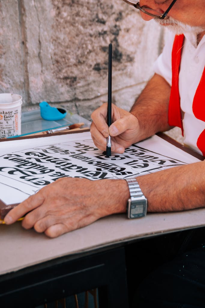Photo by Ömer Derinyar Detailed image of a man crafting hand-painted calligraphy with concentration and skill.