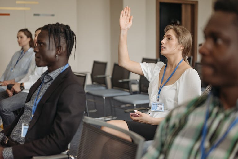 Adult woman raising hand during a business conference, showcasing engagement.