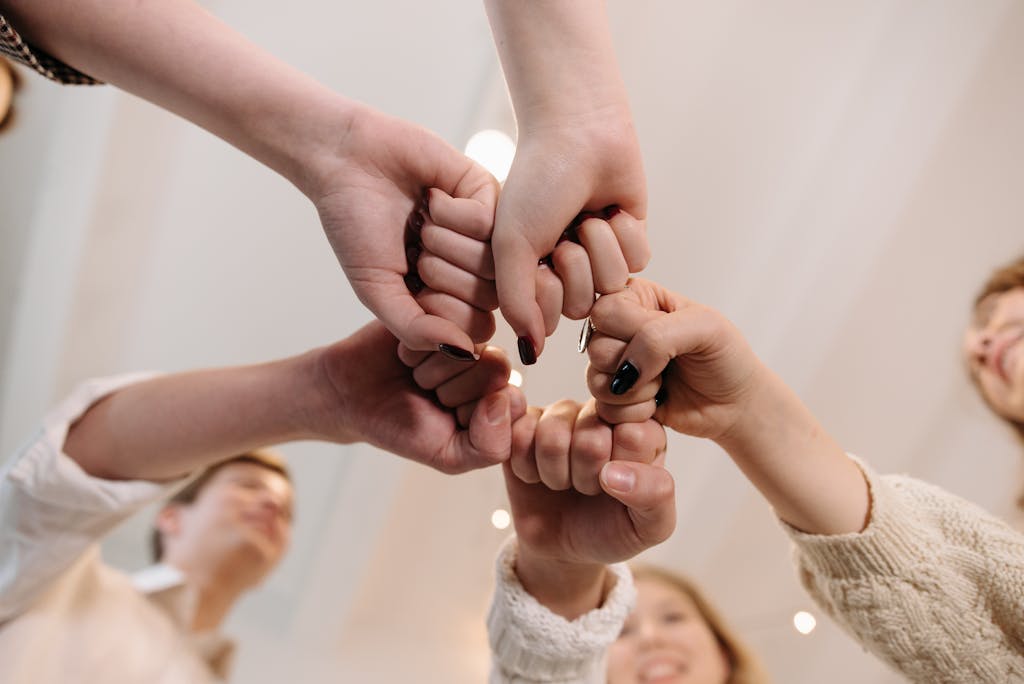 Close-up of a diverse group joining fists in a show of unity and teamwork indoors.