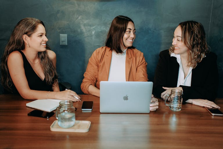 Three women sitting at a table with a laptop
