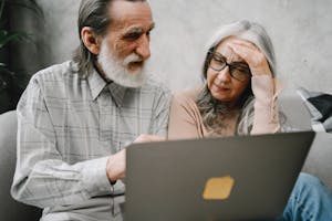 Senior couple using a laptop together at home, engaging in a focused conversation.